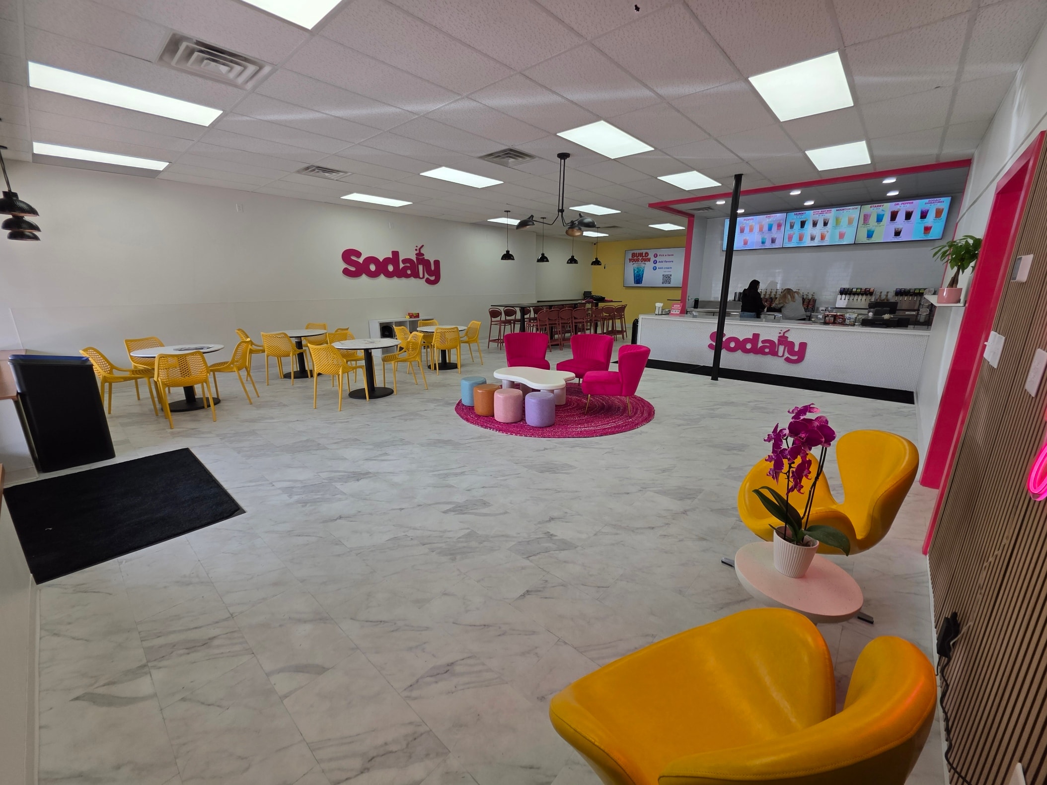 Inside Sodaly in Blaine: yellow chairs, pink seating and the Be Sodaly You neon wall